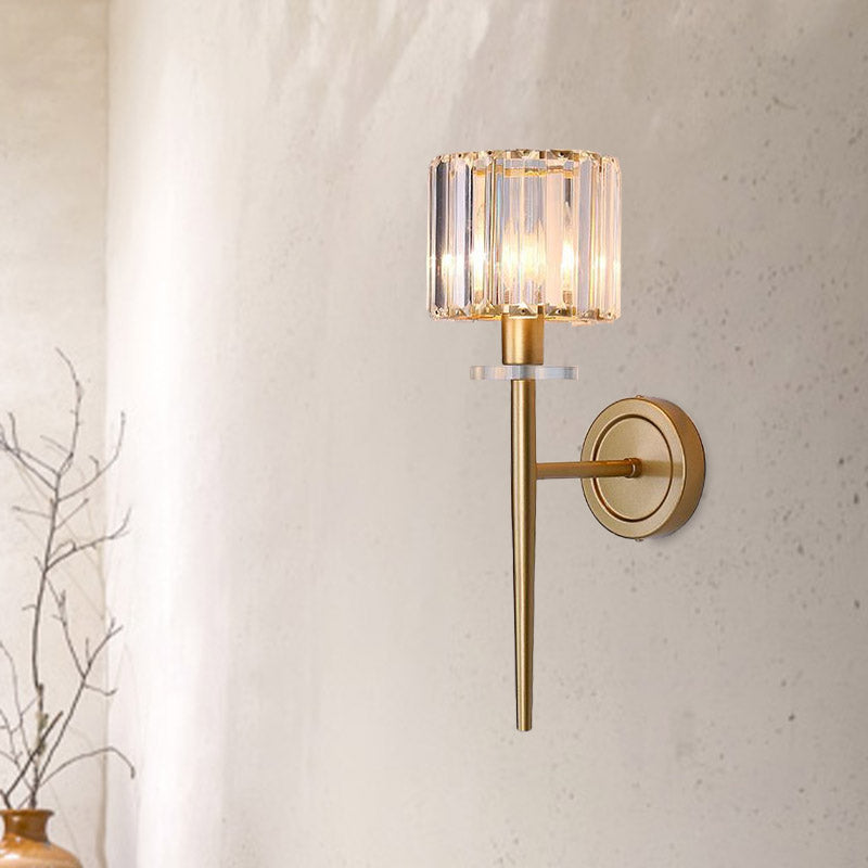 Crystal sconce lit on a pale plaster wall beside bare branches