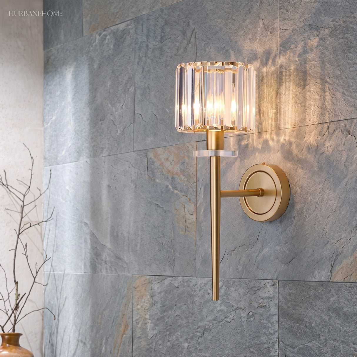 Gold crystal sconce lit on a grey slate tiled feature wall