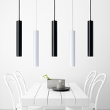 Black and white tube pendants above a white dining table