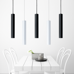 Black and white tube pendants above a white dining table