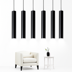 Six black tube pendants at staggered heights above an armchair
