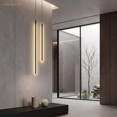 Two black cylinder pendants glowing warm against concrete by a courtyard