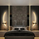 Curved LED wall light casting a soft warm glow in a dark bedroom