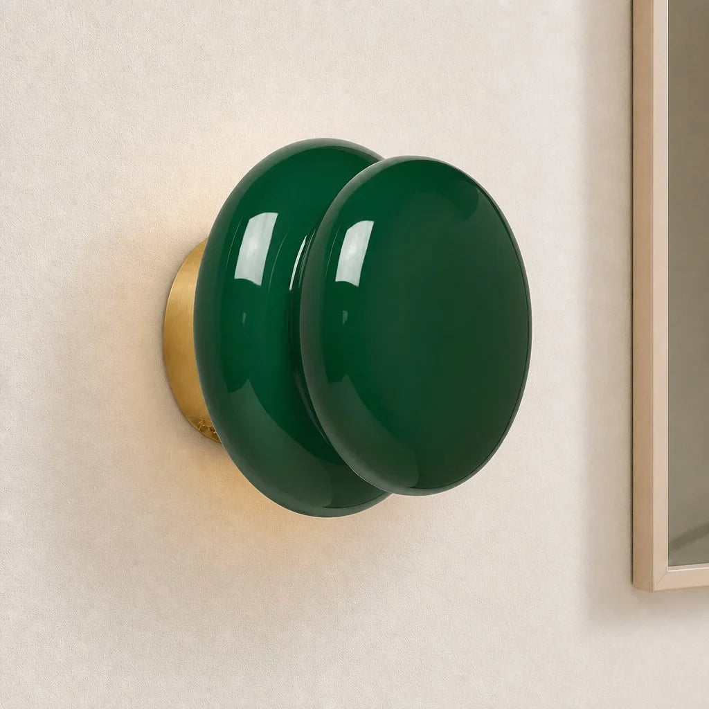 Dark green opal glass wall sconce on cream wall near mirror