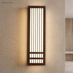 Tall dark walnut wood wall sconce casting warm light on a plaster wall