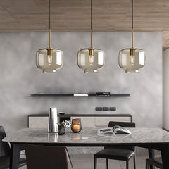 Three amber pendants above a marble kitchen island and stools