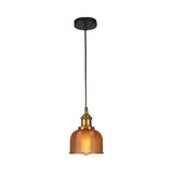 Orange gridded glass bell shade lit warm on a plain background