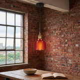 Red gridded glass pendant lit beside a factory window and brick