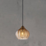 Cognac ribbed pendant with a rounded shade lit on concrete