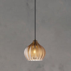 Cognac ribbed pendant with a rounded shade lit on concrete