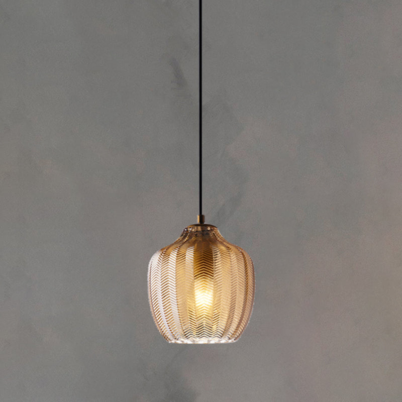 Cognac ribbed pendant lit warm against a plain grey backdrop