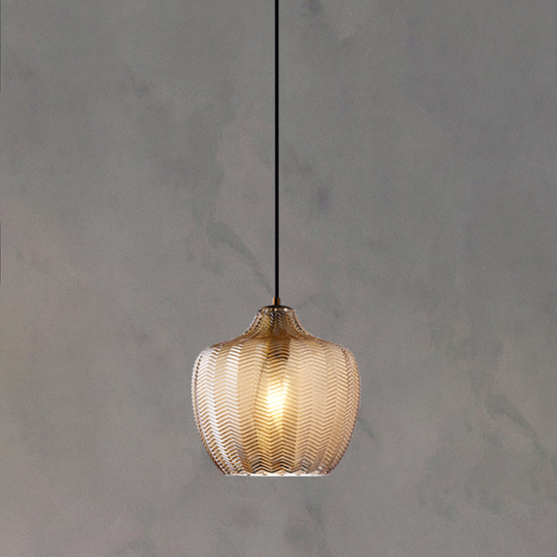 Cognac ribbed pendant with a rounded shade lit on a grey wall