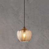Cognac ribbed pendant with a rounded shade lit on a grey wall