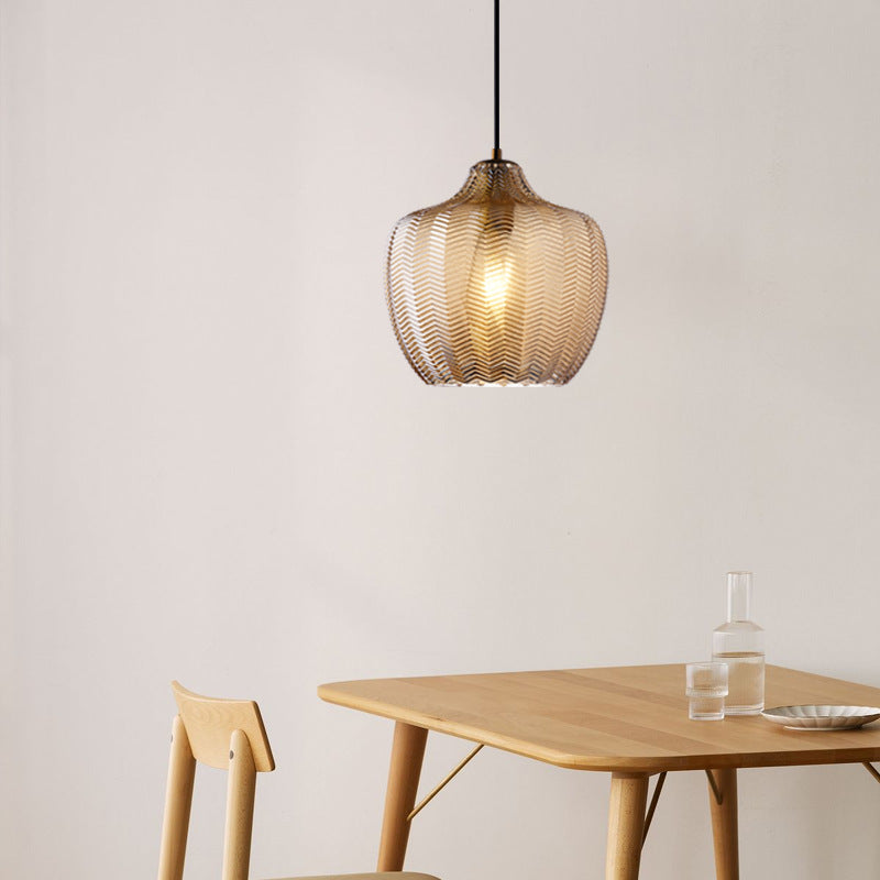 Cognac ribbed pendant lit above a pale timber dining table