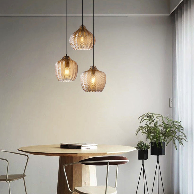 Three cognac ribbed pendants lit above a round cafe table
