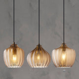 Three cognac ribbed pendants lit against a concrete wall