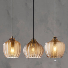 Three cognac ribbed pendants lit against a concrete wall