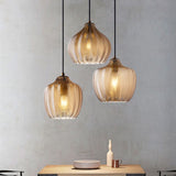 Three cognac ribbed pendants lit above a pale timber table
