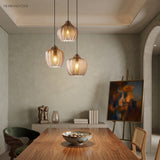 Three cognac ribbed pendants lit above a long walnut table