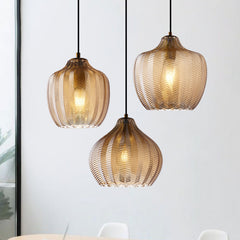 Three cognac ribbed pendants lit beside a bright window