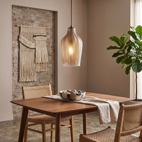 Cognac ribbed glass pendant lit above a table by a woven hanging