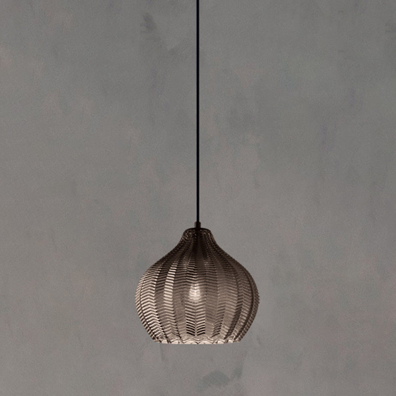 Smoke ribbed pendant lit warm against a plain grey backdrop