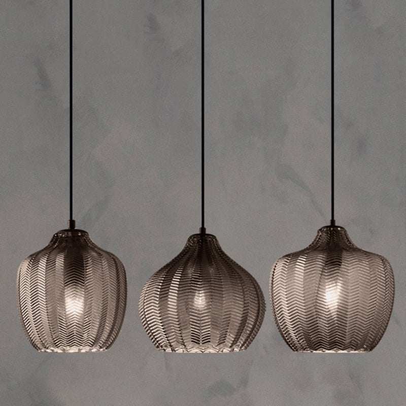Three smoke ribbed pendants lit against a concrete backdrop