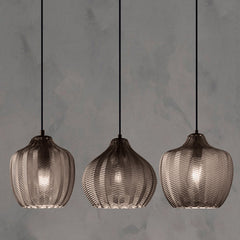 Three smoke ribbed pendants lit against a concrete backdrop