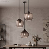 Three smoke ribbed pendants lit above a table on a grey wall