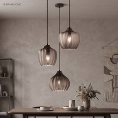 Three smoke ribbed pendants lit above a table on a grey wall