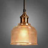 Amber ribbed glass pendant lit on a gray studio background