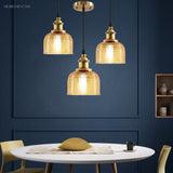 Three amber pendants over a round table against a navy wall