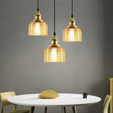 Three amber ribbed glass pendants above a round dining table