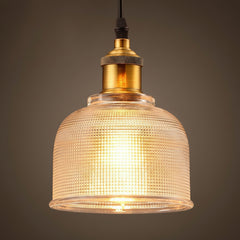 Clear bell pendant lit warm showing the ribbed glass texture