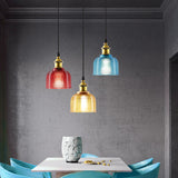 Red, amber and blue pendants over a dining table on a dark wall