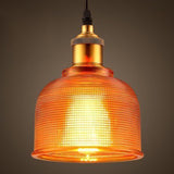 Orange ribbed glass bell pendant lit against a dark background