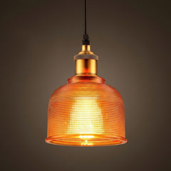 Orange ribbed glass bell pendant lit against a dark background
