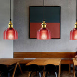 Three red ribbed glass pendants along a cafe banquette table