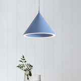 Blue cone pendant lit against white boards above a small vase