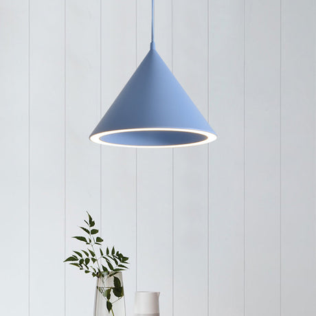 Blue cone pendant lit against white boards above a small vase