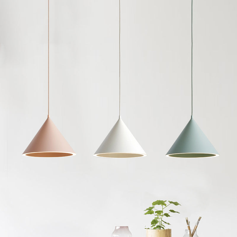 Pink and white cone pendants lit above a table beside a plant