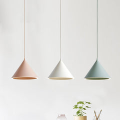 Pink and white cone pendants lit above a table beside a plant