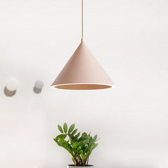 Pink cone pendant lit on a white wall above two small pots
