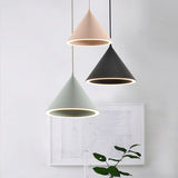 Pink, green and black cone pendants hung beside framed artwork