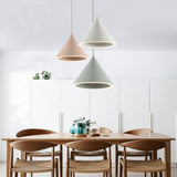 Pink, white and green cone pendants above a pale dining table
