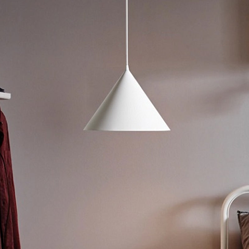 White cone pendant lit against a soft mauve coloured wall