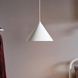 White cone pendant lit against a soft mauve coloured wall