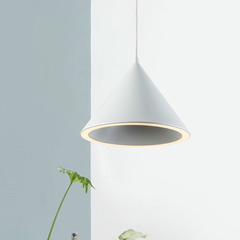 White cone pendant lit against a pale blue wall beside a plant