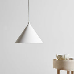 White cone pendant lit against a plain wall beside a sideboard
