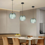 Green leaf textured glass pendant hanging above a set dining room table